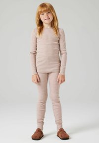 Jasnoróżowa, prążkowana bluzka z długim rękawem i dopasowane legginsy, wykonane z miękkiego materiału. Posiada okrągłe łaty na kolanach. Brązowe buty wsuwane dopełniają stylizację.