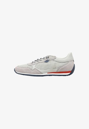 Zapatilla deportiva de gamuza gris claro y piel perforada con cordones oscuros, suela texturizada y una raya roja encima del talón sobre fondo blanco.