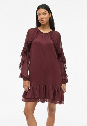 Robe bordeaux avec des manches longues à volants et un ourlet à volants en plusieurs couches. Fabriquée en tissu léger avec un design ample et fluide.