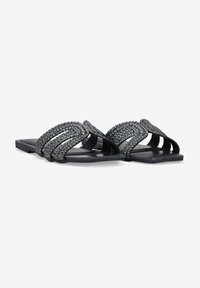 Sandali neri piatti con fasce intrecciate, design superiore testurizzato, punta aperta e suola minimalista. Adatti per un abbigliamento casual.