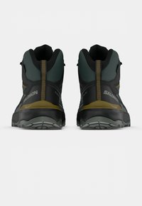 Salomon outdoor schoenen met een zwart en teal ontwerp, een gestructureerde stof, hoge enkelondersteuning en een robuuste buitenzool met een flexibel grip patroon.