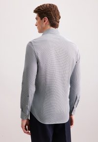 Camicia button-up in azzurro chiaro con motivo a rete. Vestibilità sagomata, maniche lunghe con polsini abbottonati, orlo curvo, realizzata in tessuto a trama.