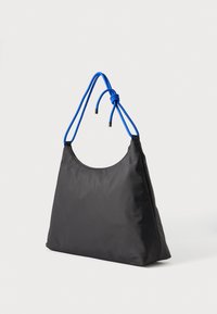 Μαύρη νάιλον τσάντα ώμου με τριγωνικό σχήμα, με μπλε χερούλια κορδονιών και ασημένιες μεταλλικές λεπτομέρειες. Λείο υλικό, μινιμαλιστικός σχεδιασμός.