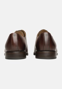 Chaussures en cuir marron avec une finition lisse, un bout arrondi et un détail de couture contrastant le long de l'arrière, dotées d'un petit talon en bois.