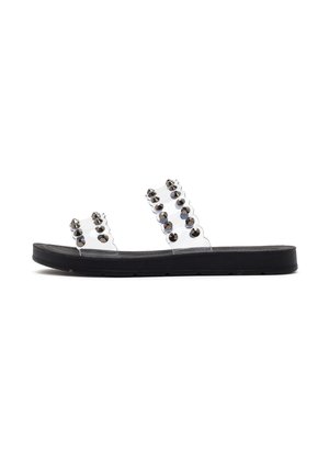 Duidelijke slide sandalen met twee banden versierd met donkere studs. Het bovenwerk is transparant, en de zool is zwart met gestructureerde details.