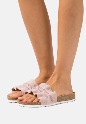 Rosa Wildlederschlupfschuhe mit einem gerafften Riemen, Korksohle und weißer Außensohle. Das offene Zehendesign zeigt Ausschnittmuster am Riemen.