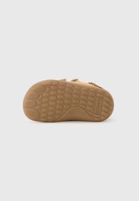 Talpa de pantof din cauciuc de culoare bej, cu un model texturat pentru aderență, având denivelări rotunde și o zonă de arc curbată. Numele brandului „PRIMIGI” embosat pe lateral.