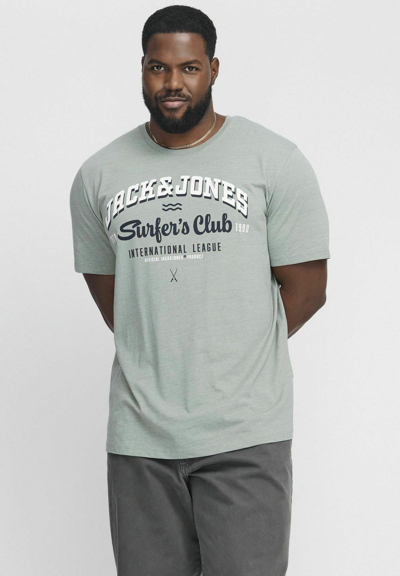 Gaiši zaļa īsām piedurknēm T-krekls ar baltiem un tumši zilajiem "Jack & Jones Surfer's Club" grafiskajiem elementiem. Mīksta tekstūra, brīva piegriezums. Pelēkas apakšdaļas komplekts.