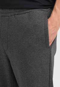 Gray sweatpants made of soft fabric feature side pockets and an elastic waistband, with a smooth texture and minimalist design.