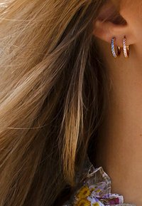 Orecchini a cerchio in rosé con accenti colorati e brillanti. Design circolare, finitura metallica liscia e dimensioni compatte. Adatti per un look casual.