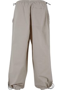Lys beige, løstsiddende bukser med elastisk talje, sidelommer og en baglomme. Har justerbare ærmer.