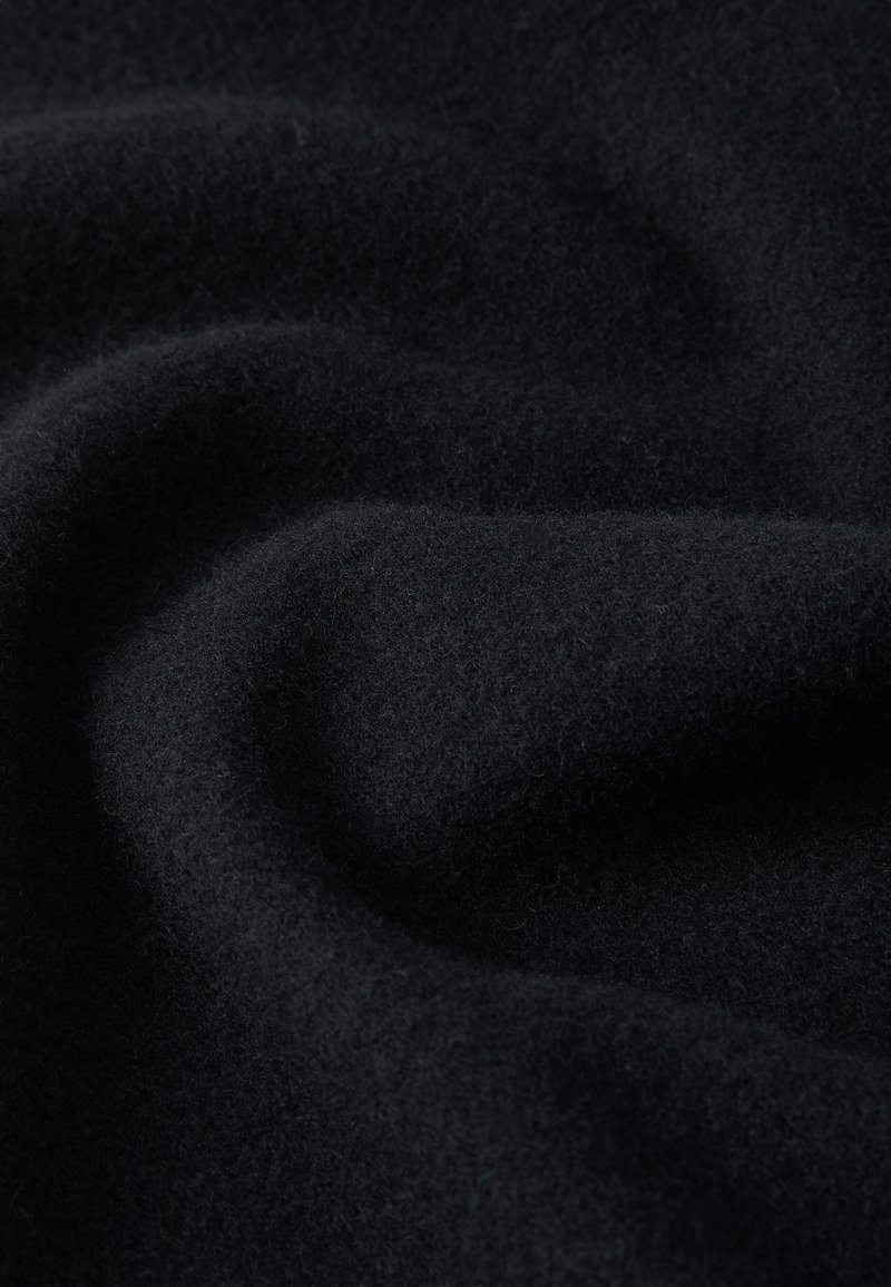 Zacht, zwart wolweefsel met subtiele plooien en textuurdetails, dat een warme en gezellige materiaalsurface toont.