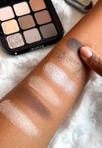 KIKO øyenskyggepalett med ni nyanser, som inneholder en blanding av matte og skinnende teksturer i nøytrale toner. Prøver på en arm viser farger fra lys til mørk.