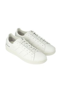 Sneakers bianchi in pelle con una superficie liscia, dotati di perforazioni sui lati, lacci piatti e un design minimalista.