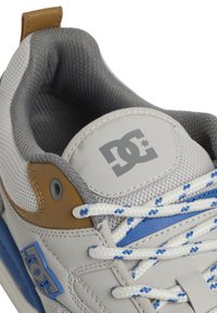 Gray sneaker with mesh and leather accents. Features blue highlights and patterned white laces. Logo detail on tongue.