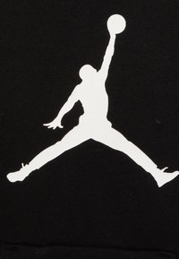 Schwarzer Stoff mit einer großen weißen Silhouette einer springenden Figur, die einen Basketball hält und eine dynamische Pose sowie klare Linien zeigt.