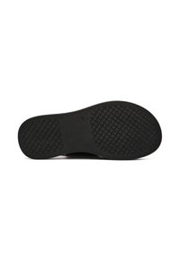 Suela de zapato negra con goma texturizada para agarre. Presenta una silueta plana y un ligero arco para soporte. Diseño minimalista sin adornos.