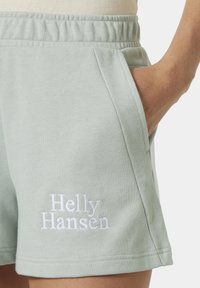 Sv�ětle zelené bavlněné šortky s volným střihem, elastickým pasem, bočními kapsami a bílým vyšitým logem "Helly Hansen" na přední straně.