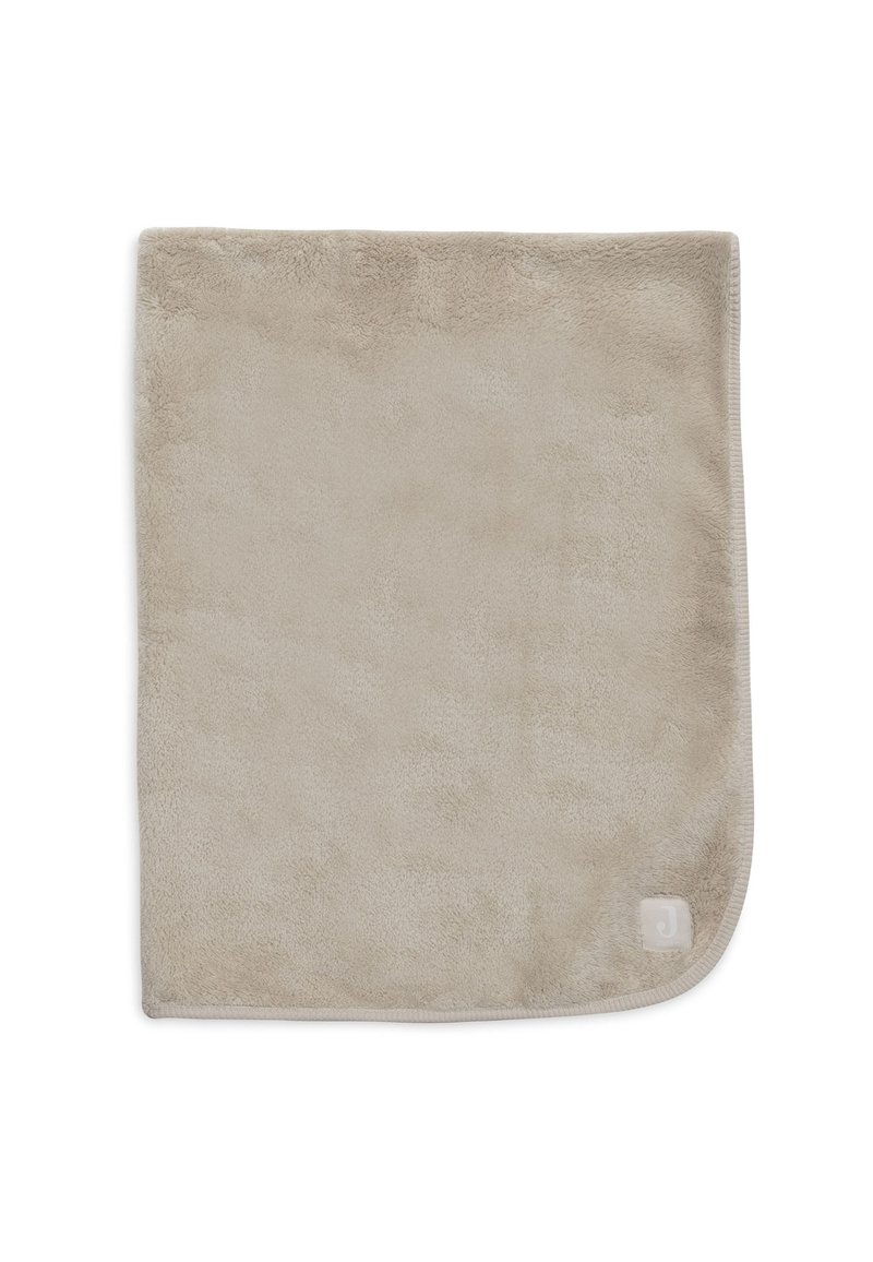 Zachte, beige pluche deken met een gladde textuur en ronde hoeken. Bevat een subtiele logo in de onderste hoek.