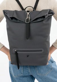 Halli graanž seljakott, mis on valmistatud tekstureeritud materjalist. Omab esist zipper taskut, reguleeritavaid rihmu ja hõbedaseid aksessuaare.