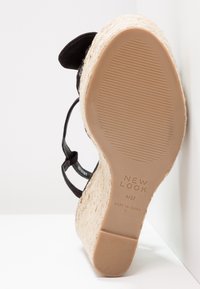 Sandale espadrille compensée avec bride de cheville noire, talon enveloppé de jute et semelle en caoutchouc marquée "New Look" taille 41/37, fabriquée en Chine.