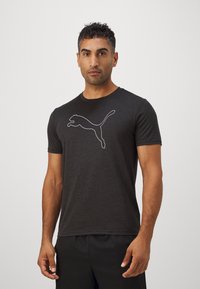 Tricou negru cu mânecă scurtă, fabricat dintr-un material moale, cu un logo alb Puma proeminent pe piept. Design simplu, cu guler de tip crew.