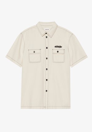 Camisa de manga corta de color beige hecha de mezcla de algodón, con botones negros, dos bolsillos en el pecho y costuras negras contrastantes. Logo en el bolsillo izquierdo.