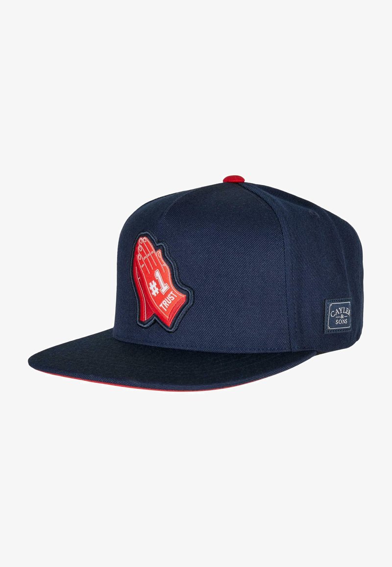 Navy blue cap with a flat brim, featuring a red hand graphic and "#1 TRUST" text. Made of textured fabric, with logo patch on the side.