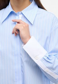 Light blue striped shirt with a classic collar and white cuffs. Features vertical stripes and buttoned cuffs, made from a smooth fabric.