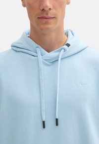 Felpa leggera blu con cappuccio realizzata in tessuto morbido, dotata di cappuccio regolabile, logo frontale e dettagli di cucitura discreti.