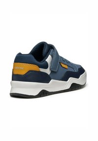 Sneaker blu navy con cinturino in velcro, dotato di un accento giallo a contrasto, suola in gomma nera e pannelli in tessuto testurizzato per una maggiore durata.