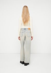 Šviesiai mėlynos, aukšto liemens džinsai su laisvu kirpimu, su švelniu išblukimu, dviem galinėmis kišenėmis ir pažymėta odine etiketė ant liemens.