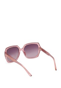 Gafas de sol hexagonales con un marco transparente de color rosa claro, lentes oscuros en degradado y varillas delgadas rosas con una sutil marca.