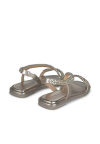 Sandali metallici argento con decorazioni in strass, cinturini incrociati e suola piatta. Texture liscia con dettagli di design minimi.