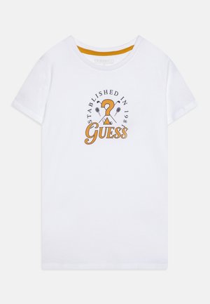 Weißes T-Shirt mit kurzen Ärmeln und rundem Halsausschnitt, mit orange-schwarzem "Guess"-Logo, Tennisschlägern und dem Schriftzug "Established in 1981" auf der Vorderseite.