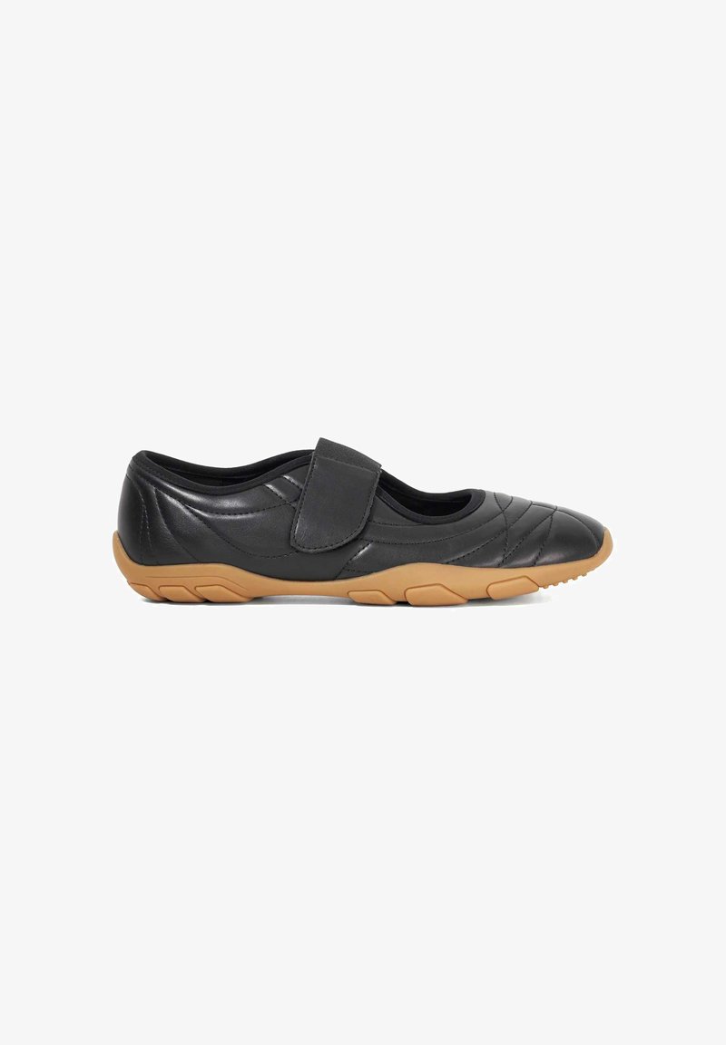Black leather shoe with quilted design, Velcro strap, and a tan rubber sole featuring a textured grip pattern. Low-profile and lightweight.