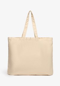 Sac fourre-tout en toile de couleur blanc cassé, avec deux longues poignées, une forme rectangulaire simple et une surface en tissu texturé.