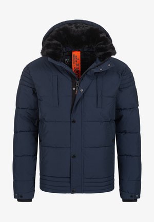 Dunkelblaues Steppjacke mit einer Kapuze aus Kunstfell, Reißverschluss und Knopfverschluss, Fronttaschen und gestepptem Design. Leuchtend orangefarbener Innenetikett.