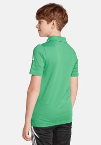 Grüne Polohemden mit Kragen und kurzen Ärmeln, aus einem glatten Material. Die Rückansicht zeigt ein einfaches Design ohne sichtbare Logos oder Muster.