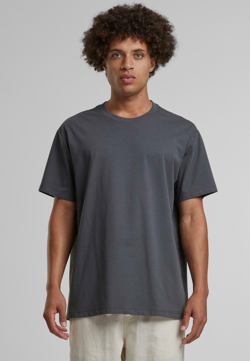 Šedé bavlněné tričko s krátkými rukávy, kulatým výstřihem a volným střihem. Má hladkou texturu a minimalistický design.