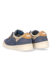 Par de zapatillas informales de denim azul y beige de corte bajo con suelas blancas y marca "Lois" en parches de talón color marrón.