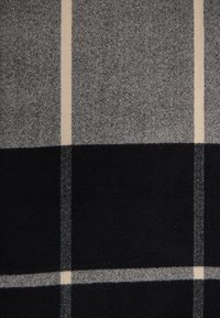 Szaro-czarny koc w kratę o wyraźnej fakturze, z wyraźnymi paskami na miękkim tle i gładkim wykończeniu.