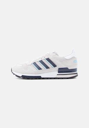 Lavtop atletiksneaker i lys grå med marineblå og lyseblå striber, tekstureret mesh og ruskindspaneler, hvid sål med sort slidbane.