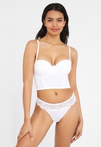 White lingerie set featuring a padded, underwire bra with a sheer bodice and lace accents. Also includes a matching lace-trimmed thong.