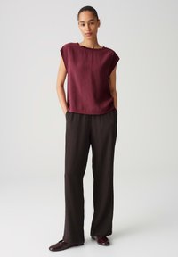 Top bordeaux con una vestibilità rilassata e maniche corte, abbinato a pantaloni larghi plissettati neri. Tessuto morbido, design minimalista.