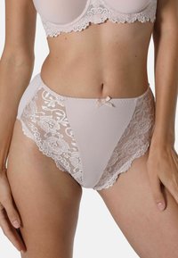 Hochgeschnittene rosa Unterwäsche mit Spitze, gewellten Kanten und einer Schleifendetail in der Mitte. Weicher Stoff mit einer glatten Textur.