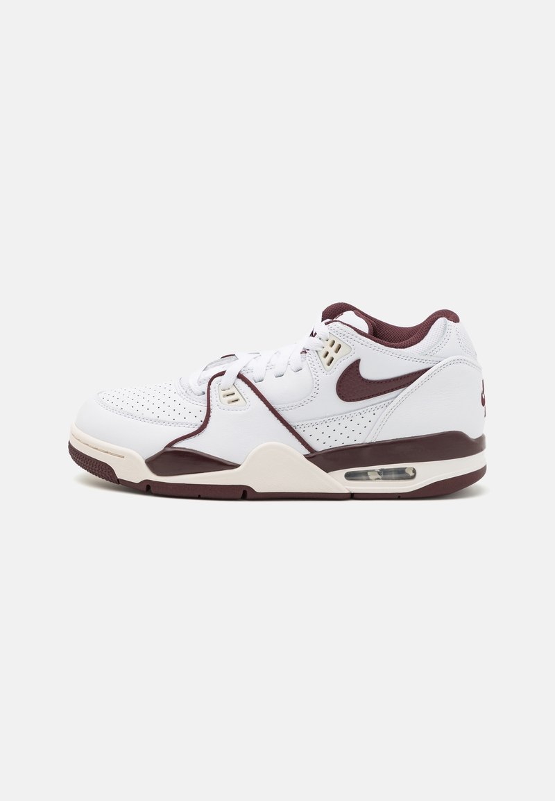 Baskets Nike Air blanches et bordeaux avec embout perforé, semelle intermédiaire à coussin d'air visible, et design à lacets sur fond uni.