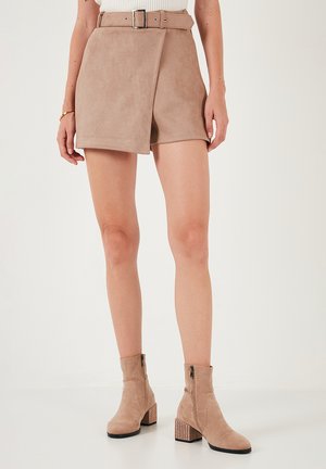 Beige faux suede hoge taille shorts met een voorste wikkelontwerp en een bijpassende riem. Draagt bij beige enkellaarsjes met een gestructureerde hak.