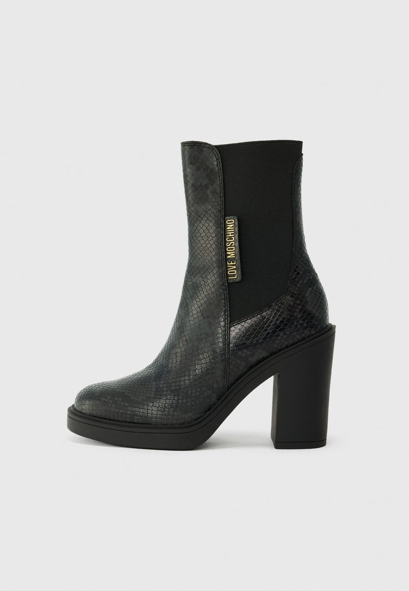 Botas de tornozelo pretas com um padrão de pele de cobra texturizado e brilhante, apresentando um salto bloco e painéis laterais elásticos com um detalhe de logotipo dourado.