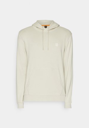 Lys beige hettegenser i myk stoff, med frontlomme, snorhette og liten logo-patch på brystet.
